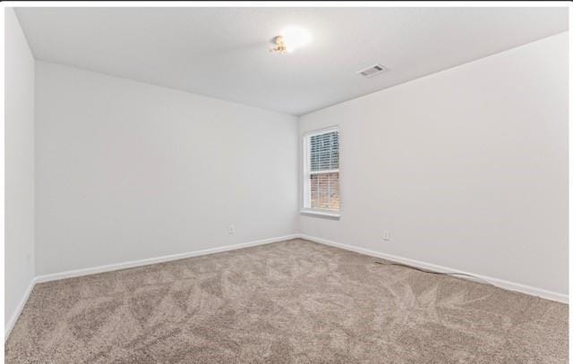 spare room with visible vents, light carpet, and baseboards