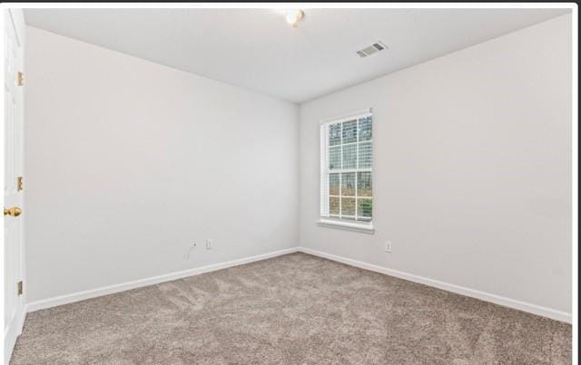 empty room featuring light colored carpet, visible vents, and baseboards