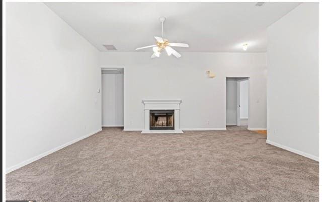 unfurnished living room with ceiling fan, baseboards, a fireplace with raised hearth, and light colored carpet