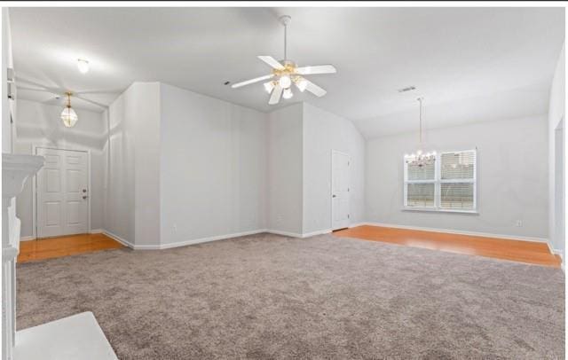 empty room featuring carpet floors, vaulted ceiling, baseboards, and ceiling fan with notable chandelier