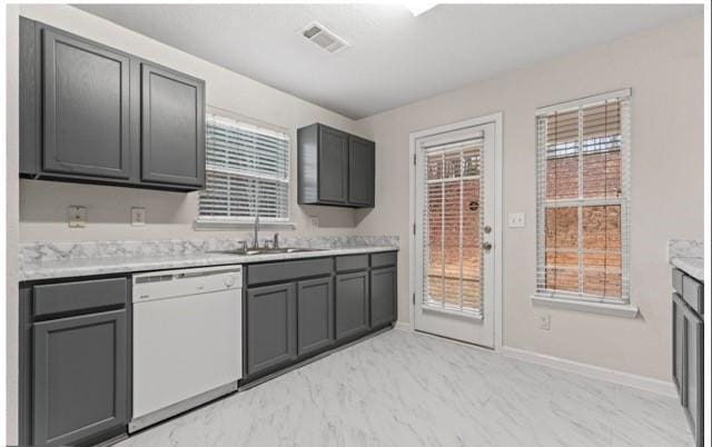 kitchen with marble finish floor, light countertops, visible vents, white dishwasher, and a sink