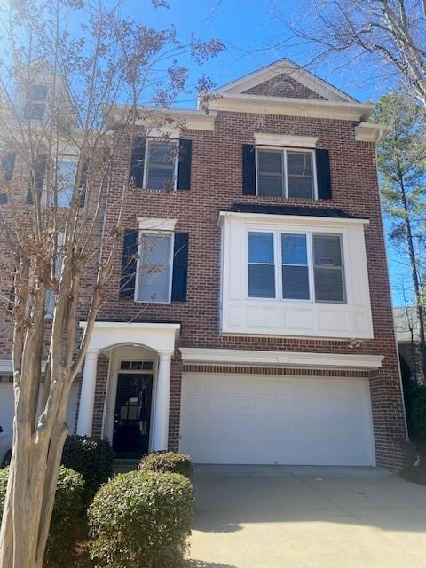 view of front facade with brick siding, driveway, and an attached garage