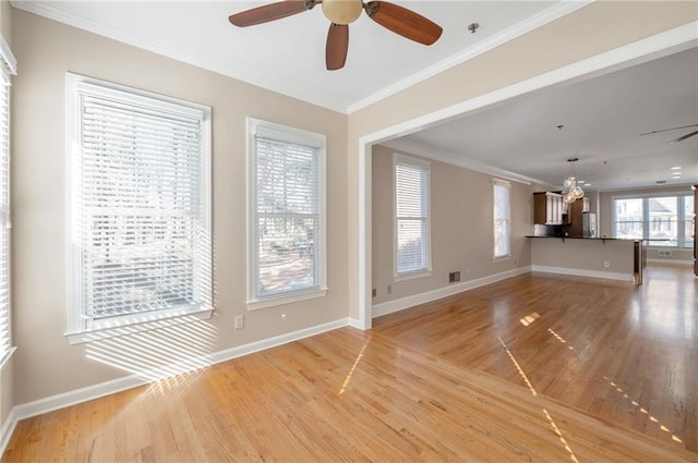 unfurnished living room featuring ceiling fan with notable chandelier, crown molding, light wood-style flooring, and baseboards