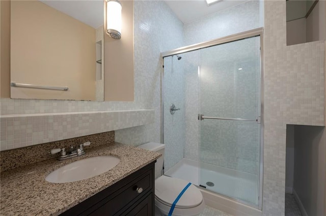 full bathroom with decorative backsplash, tile walls, toilet, vanity, and a stall shower