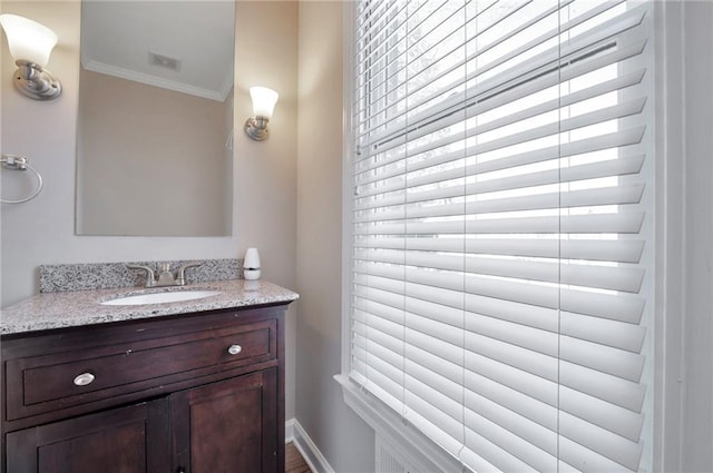 bathroom with vanity, ornamental molding, and baseboards