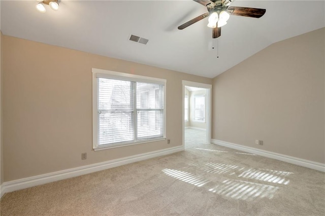 empty room featuring vaulted ceiling, baseboards, visible vents, a ceiling fan, and light carpet