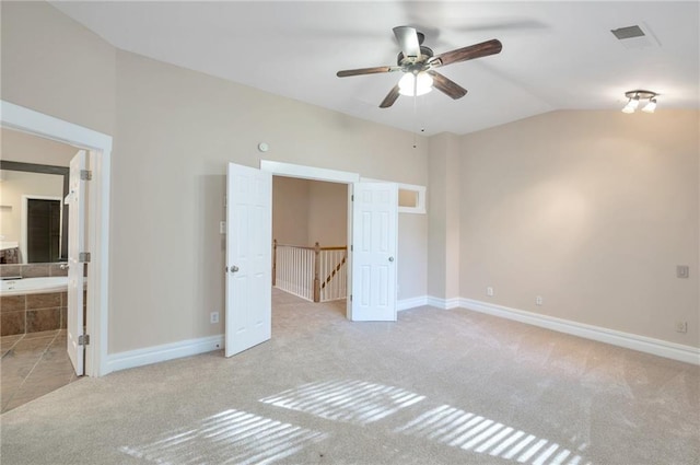 unfurnished bedroom featuring baseboards, carpet floors, lofted ceiling, and visible vents