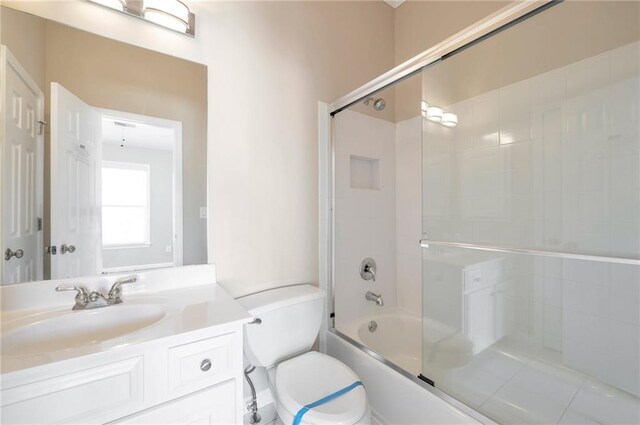 full bathroom with bath / shower combo with glass door, toilet, and vanity