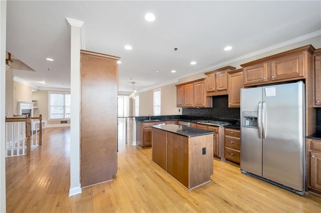 kitchen featuring brown cabinets, crown molding, a kitchen island, and appliances with stainless steel finishes