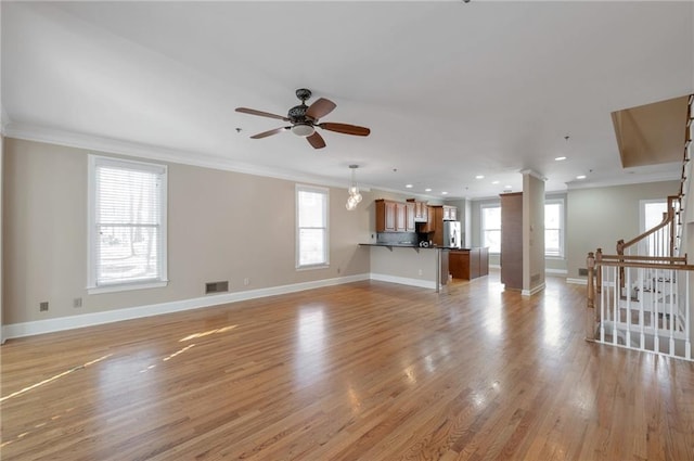 unfurnished living room featuring a ceiling fan, light wood-style flooring, baseboards, visible vents, and ornamental molding