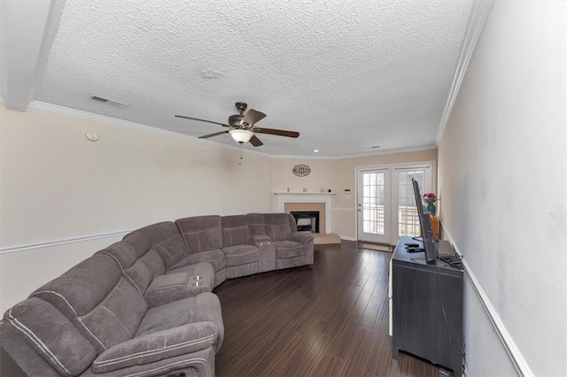 living room featuring crown molding, dark wood-type flooring, ceiling fan, and a textured ceiling