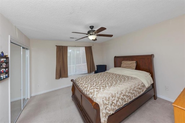 bedroom featuring ceiling fan, light colored carpet, a closet, and a textured ceiling