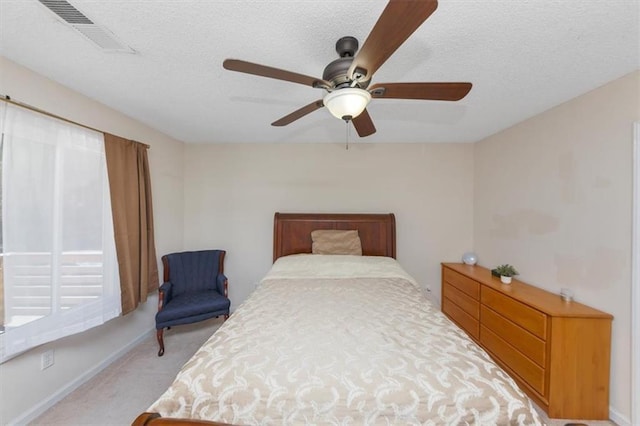 carpeted bedroom featuring ceiling fan and a textured ceiling