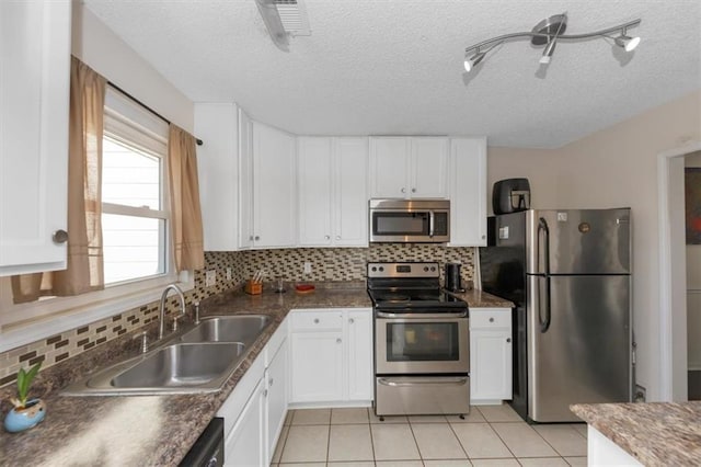 kitchen featuring white cabinetry, sink, decorative backsplash, light tile patterned floors, and stainless steel appliances