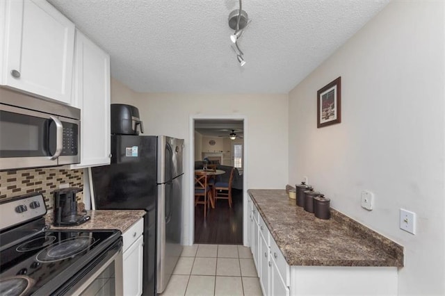 kitchen featuring light tile patterned floors, appliances with stainless steel finishes, white cabinetry, a textured ceiling, and decorative backsplash