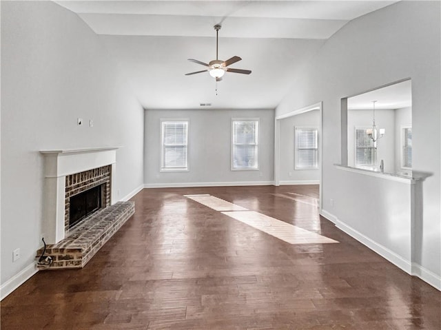 unfurnished living room with a fireplace, ceiling fan with notable chandelier, dark hardwood / wood-style floors, and a healthy amount of sunlight