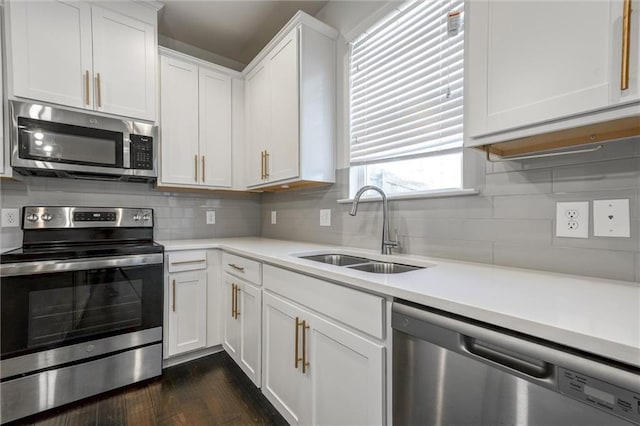 kitchen featuring dark wood finished floors, light countertops, appliances with stainless steel finishes, white cabinetry, and a sink