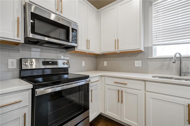 kitchen featuring a sink, backsplash, white cabinetry, appliances with stainless steel finishes, and light countertops