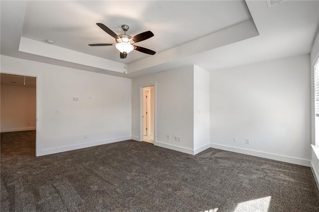 unfurnished room featuring dark carpet, baseboards, a raised ceiling, and ceiling fan