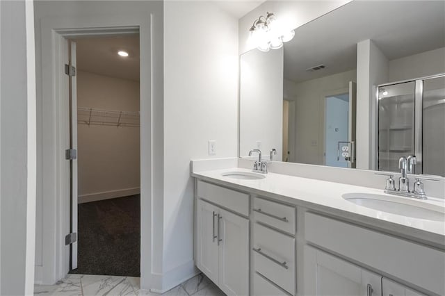 bathroom featuring a spacious closet, marble finish floor, a stall shower, and a sink