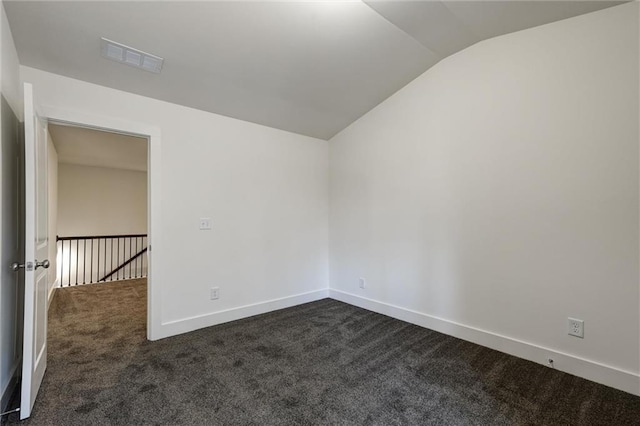 spare room with visible vents, baseboards, dark carpet, and vaulted ceiling