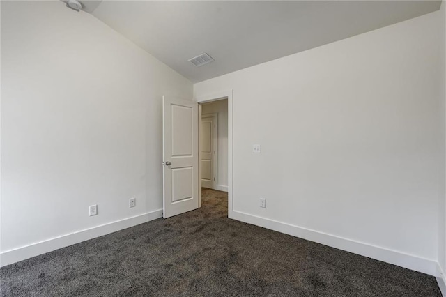 spare room with visible vents, dark carpet, baseboards, and vaulted ceiling