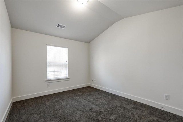 spare room featuring visible vents, lofted ceiling, baseboards, and dark carpet