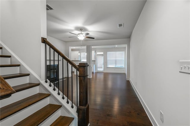 stairway featuring wood finished floors, a ceiling fan, visible vents, and baseboards