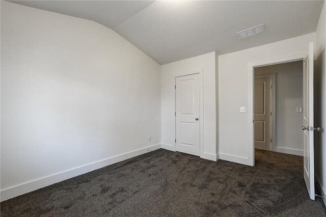 unfurnished bedroom featuring visible vents, baseboards, dark carpet, and vaulted ceiling