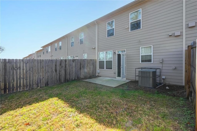 rear view of house with central air condition unit, a lawn, and a fenced backyard