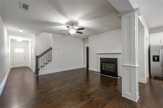 unfurnished living room with visible vents, dark wood-style floors, and decorative columns