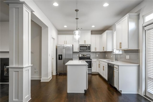 kitchen featuring a sink, dark wood finished floors, a center island, appliances with stainless steel finishes, and light countertops