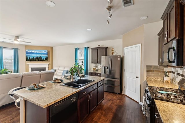 kitchen featuring sink, a kitchen island with sink, dark hardwood / wood-style floors, black appliances, and decorative backsplash