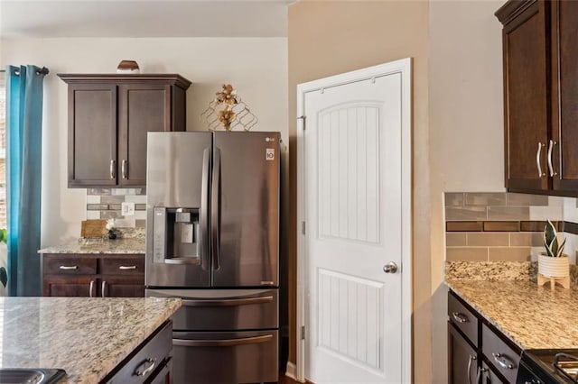 kitchen featuring stainless steel fridge with ice dispenser, decorative backsplash, dark brown cabinets, and light stone countertops