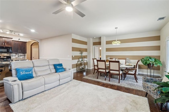 living room featuring ceiling fan and dark hardwood / wood-style flooring