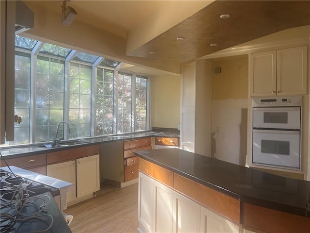 kitchen featuring double oven, dark countertops, a healthy amount of sunlight, and a sunroom