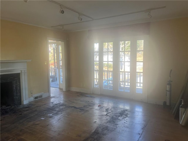 unfurnished living room featuring a high end fireplace, track lighting, and visible vents