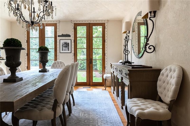 dining space featuring a notable chandelier, french doors, and light hardwood / wood-style floors