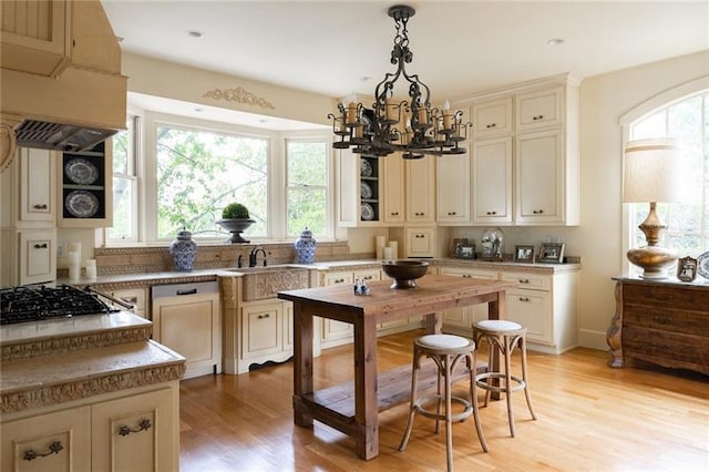 kitchen with pendant lighting, light hardwood / wood-style flooring, stainless steel gas cooktop, tasteful backsplash, and a chandelier