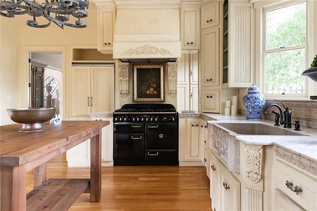 kitchen featuring a healthy amount of sunlight, premium range hood, high end range, and light hardwood / wood-style flooring