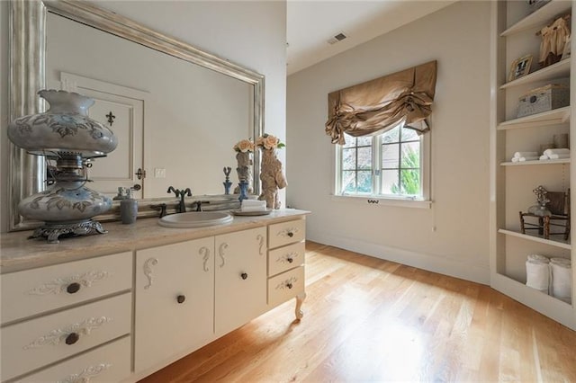 bathroom with built in features, hardwood / wood-style flooring, and vanity