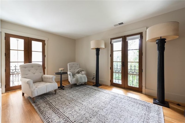 sitting room with light wood-type flooring, french doors, and a wood stove