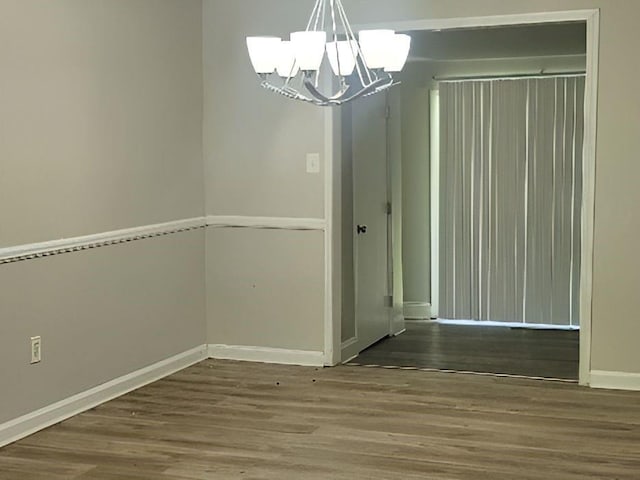 unfurnished dining area with wood-type flooring and an inviting chandelier