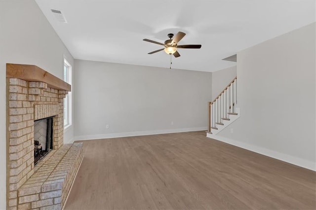 unfurnished living room featuring ceiling fan, hardwood / wood-style floors, and a brick fireplace