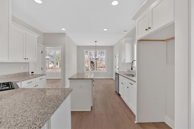 kitchen with stainless steel dishwasher, light stone countertops, sink, and white cabinets