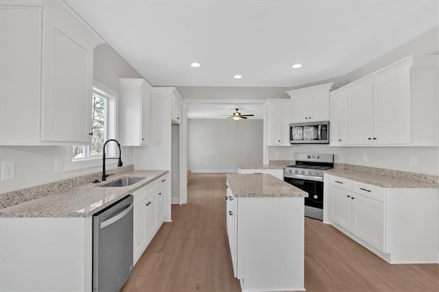 kitchen featuring sink, white cabinetry, light stone counters, a kitchen island, and stainless steel appliances