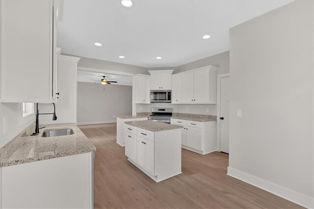 kitchen featuring sink, light hardwood / wood-style flooring, appliances with stainless steel finishes, white cabinetry, and kitchen peninsula