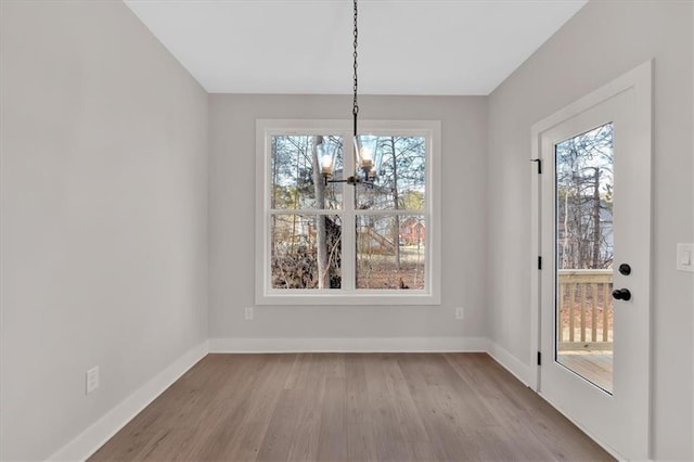 unfurnished dining area featuring a healthy amount of sunlight, light hardwood / wood-style flooring, and a notable chandelier