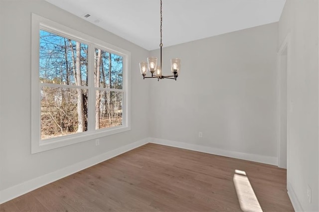 unfurnished dining area with hardwood / wood-style floors and an inviting chandelier