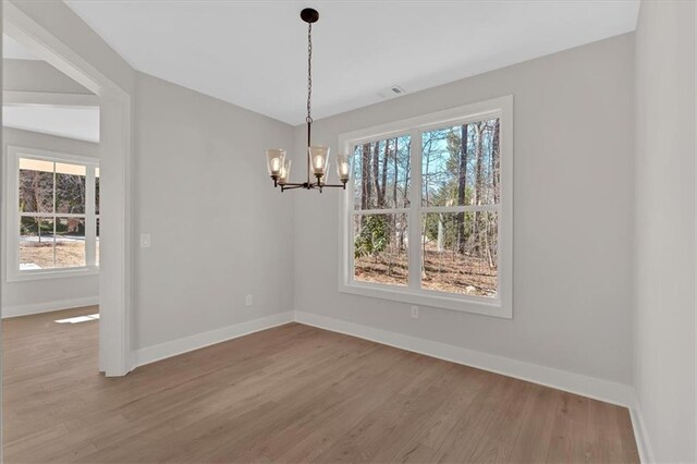 unfurnished dining area with an inviting chandelier and wood-type flooring